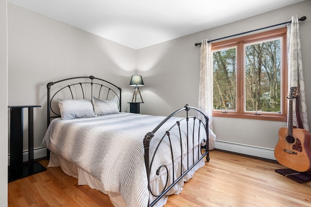 bedroom with baseboard heating, a baseboard heating unit, and wood finished floors