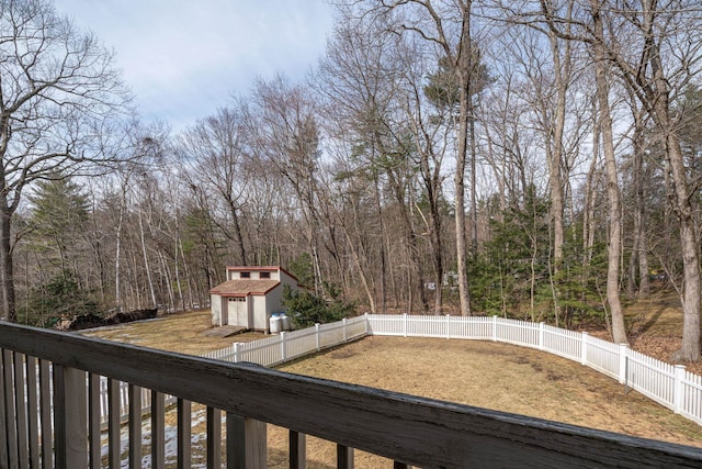 view of yard featuring an outbuilding, a fenced backyard, and a forest view