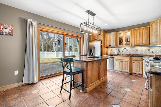 kitchen with a sink, a kitchen island, backsplash, stainless steel appliances, and glass insert cabinets