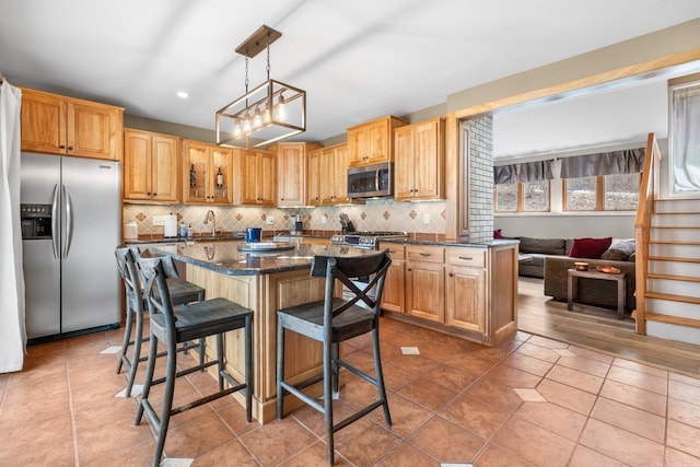 kitchen with a sink, backsplash, a center island, appliances with stainless steel finishes, and a breakfast bar area