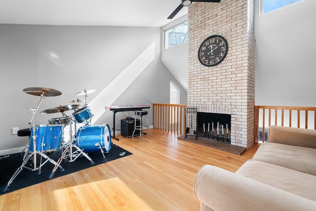 playroom featuring a brick fireplace, baseboards, ceiling fan, and wood finished floors