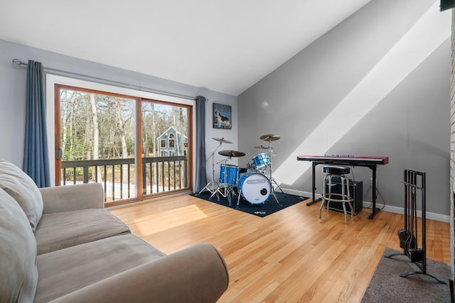 interior space with baseboards, wood finished floors, and vaulted ceiling