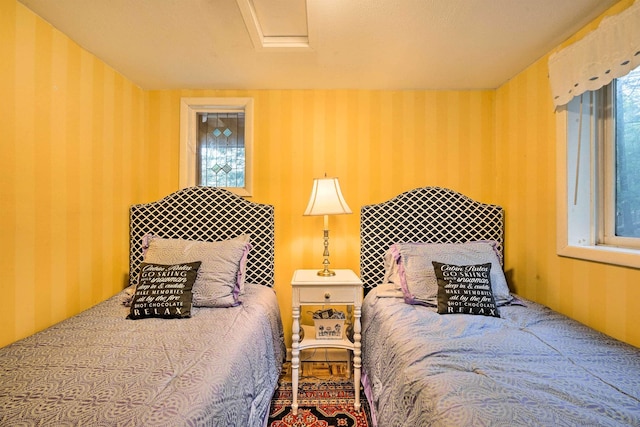 bedroom featuring wallpapered walls and multiple windows