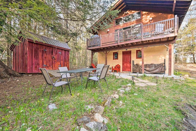 back of house with outdoor dining space, a shed, stucco siding, an outdoor structure, and a deck