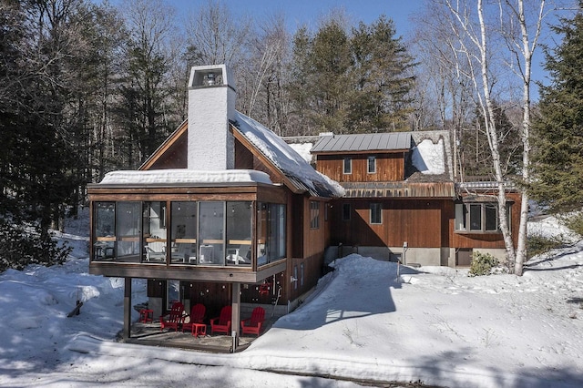 snow covered property featuring a chimney and a sunroom