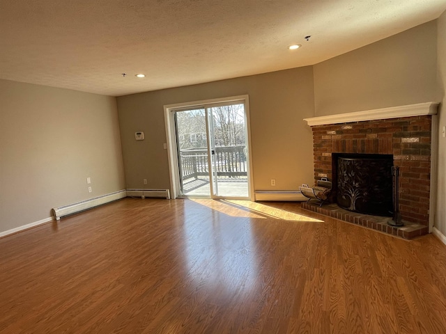 unfurnished living room with a brick fireplace, a baseboard heating unit, baseboards, and wood finished floors