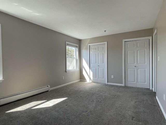 unfurnished bedroom with carpet flooring, baseboards, multiple closets, and baseboard heating