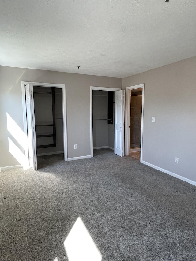 unfurnished bedroom with baseboards, two closets, and carpet