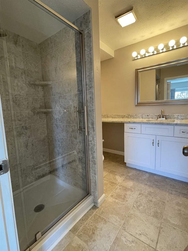 bathroom with vanity, baseboards, a stall shower, a textured ceiling, and toilet