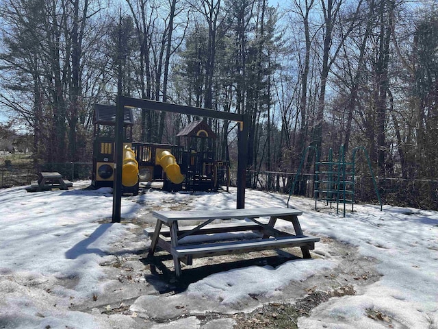 snow covered playground featuring playground community and fence