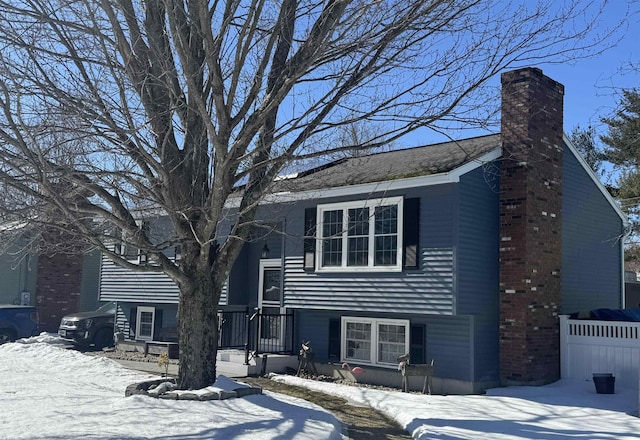 split foyer home featuring fence and a chimney