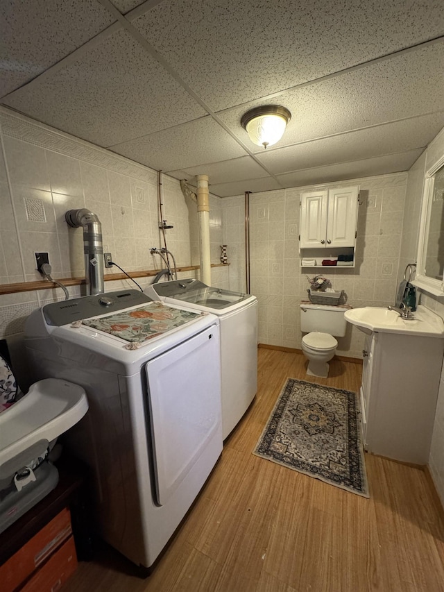 clothes washing area featuring washer and clothes dryer, laundry area, light wood-type flooring, and a sink