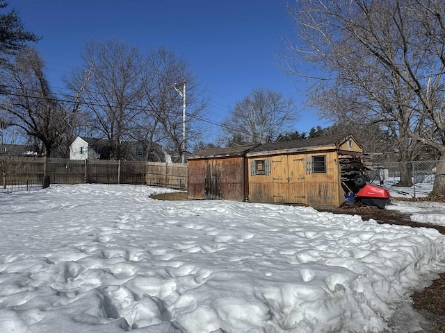 yard covered in snow with an outdoor structure and fence