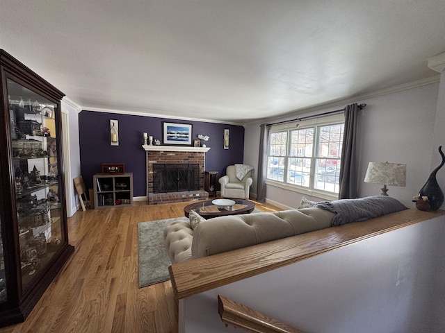 living area with ornamental molding, a fireplace, baseboards, and wood finished floors