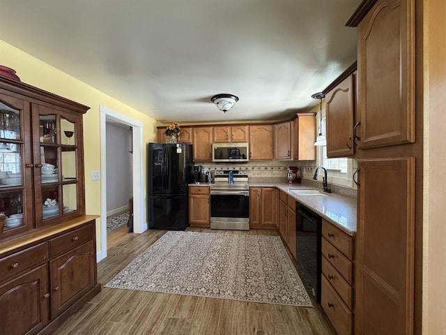 kitchen with a sink, backsplash, black appliances, and wood finished floors