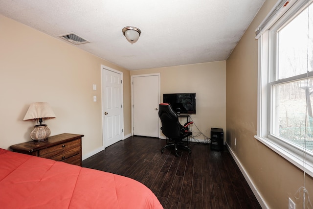 bedroom with visible vents, baseboards, and wood finished floors