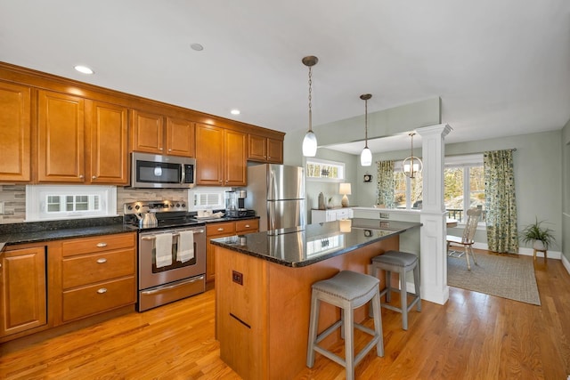 kitchen featuring a wealth of natural light, a kitchen breakfast bar, backsplash, a center island, and appliances with stainless steel finishes