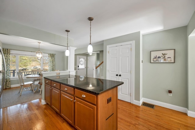 kitchen featuring light wood-type flooring, baseboards, visible vents, and a kitchen island