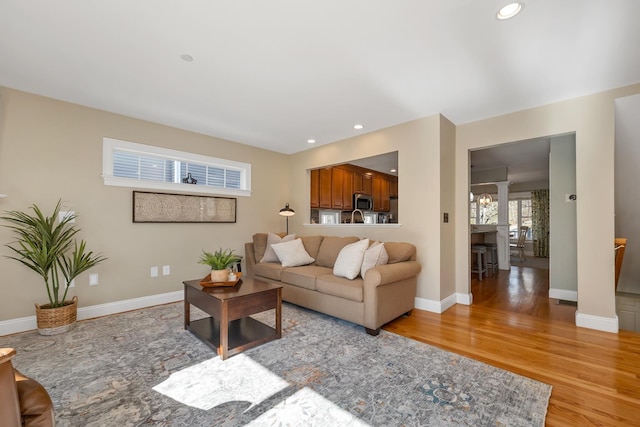 living area with recessed lighting, light wood-style flooring, baseboards, and ornate columns