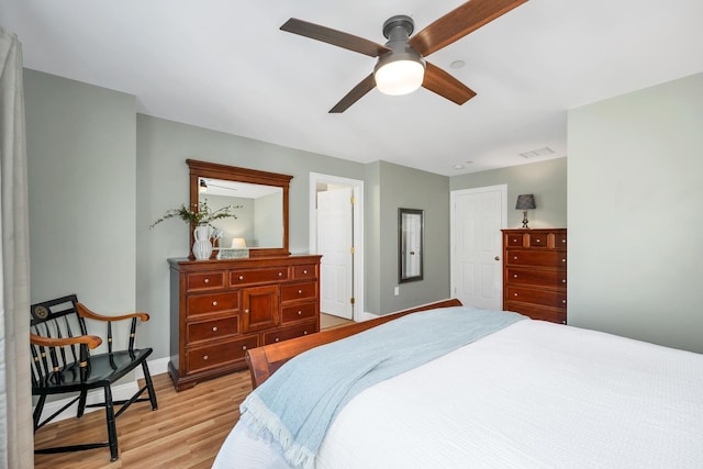 bedroom with light wood finished floors, visible vents, ceiling fan, and baseboards