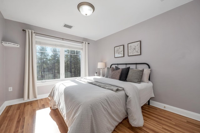 bedroom featuring visible vents, baseboards, and wood finished floors