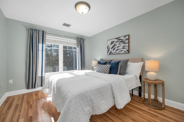 bedroom featuring wood finished floors, visible vents, and baseboards