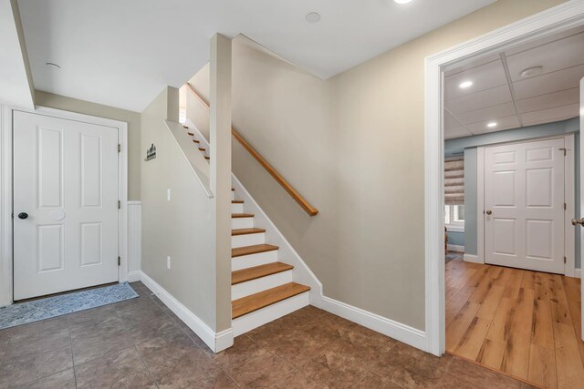 stairs featuring recessed lighting, a paneled ceiling, and baseboards