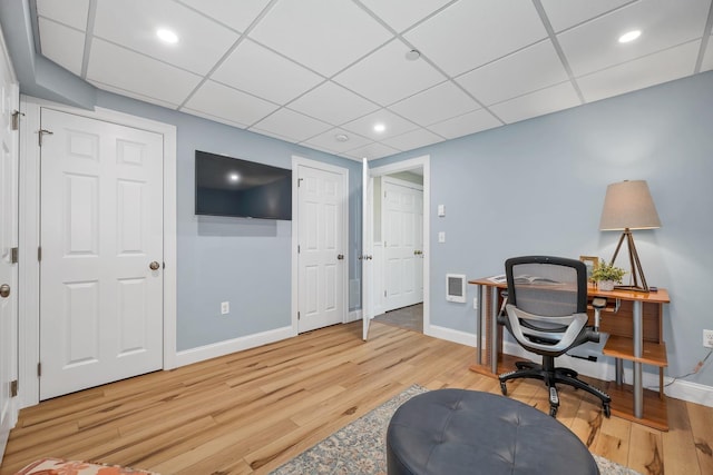 office space featuring a drop ceiling, light wood-type flooring, baseboards, and visible vents