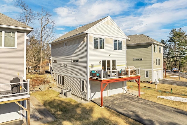 rear view of property with a deck, aphalt driveway, central air condition unit, and a garage