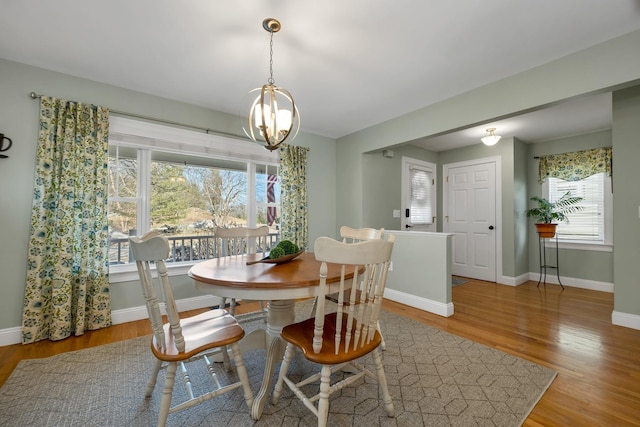 dining space with baseboards, an inviting chandelier, and wood finished floors