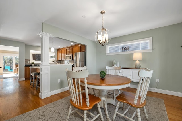 dining space with light wood-type flooring, baseboards, and an inviting chandelier