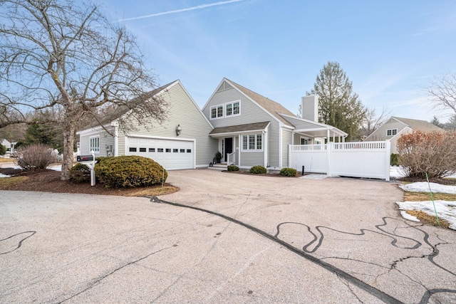 view of front facade with driveway, a chimney, and an attached garage