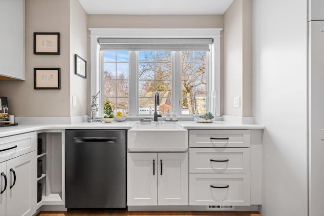 kitchen with stainless steel dishwasher, light countertops, white cabinets, and a sink