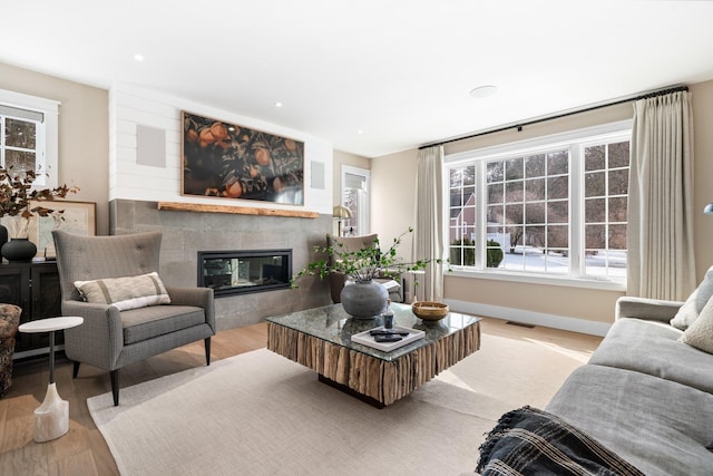 living area with visible vents, recessed lighting, a tile fireplace, and wood finished floors