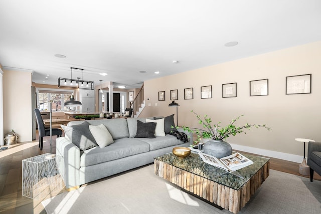 living room featuring stairs, wood finished floors, and baseboards