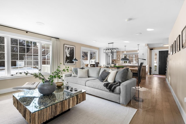 living room with recessed lighting, baseboards, and light wood-type flooring