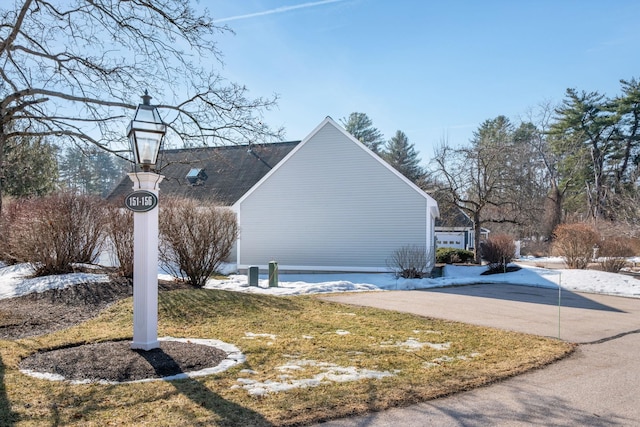 view of side of home featuring a lawn and concrete driveway