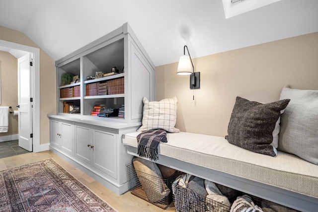 interior space featuring light wood finished floors, ensuite bath, and vaulted ceiling