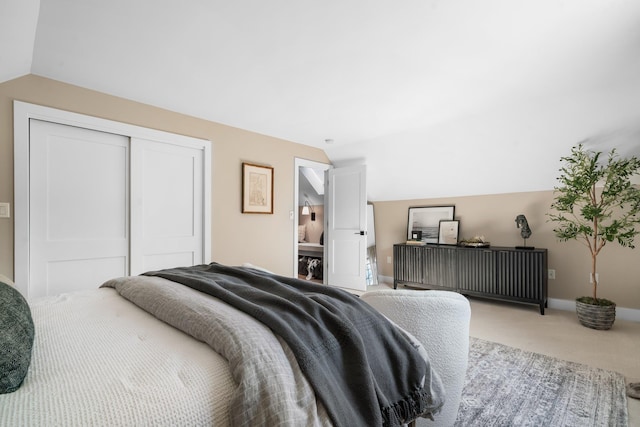 carpeted bedroom with a closet, lofted ceiling, and baseboards