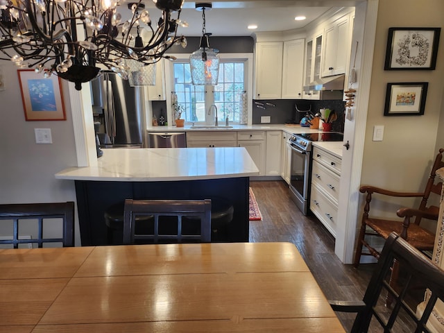 kitchen with under cabinet range hood, dark wood-style floors, white cabinets, stainless steel appliances, and a sink