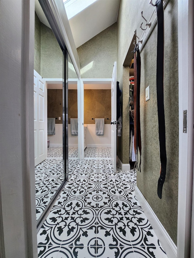 hallway featuring vaulted ceiling and baseboards