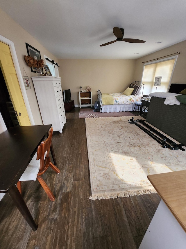 bedroom featuring a barn door, ceiling fan, and wood finished floors