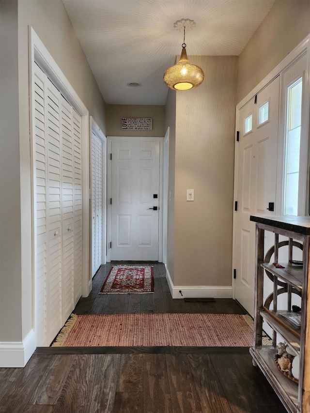 foyer featuring visible vents, baseboards, and dark wood finished floors