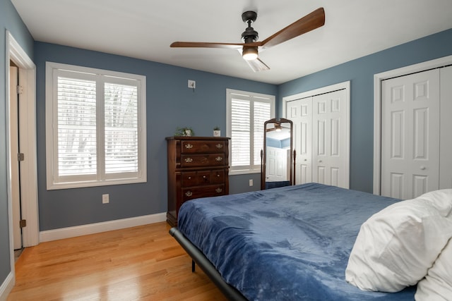 bedroom with multiple windows, multiple closets, baseboards, and light wood-style flooring