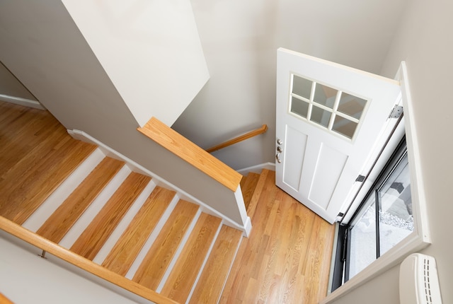 stairway with baseboard heating and wood finished floors