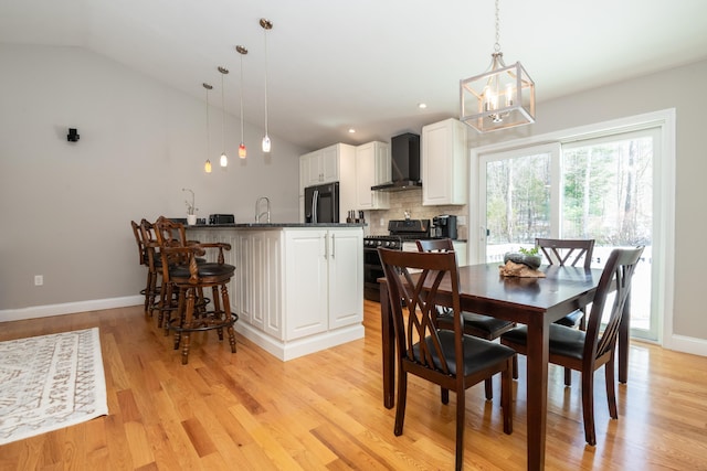 dining space featuring recessed lighting, an inviting chandelier, light wood finished floors, baseboards, and vaulted ceiling