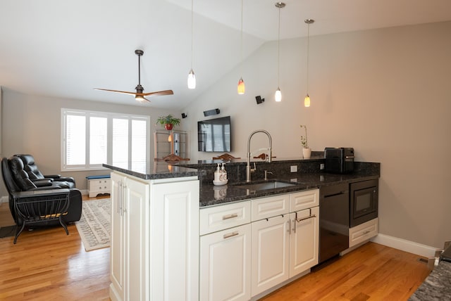 kitchen with a sink, a peninsula, open floor plan, and light wood finished floors