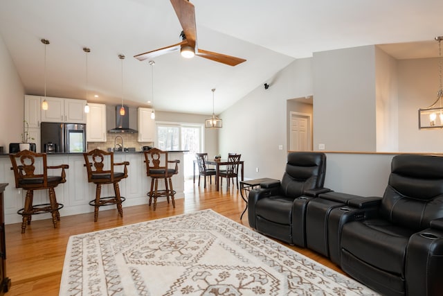 living area with lofted ceiling, light wood-style floors, and a ceiling fan