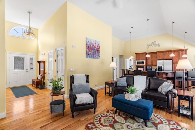 living room with baseboards, light wood-type flooring, and high vaulted ceiling