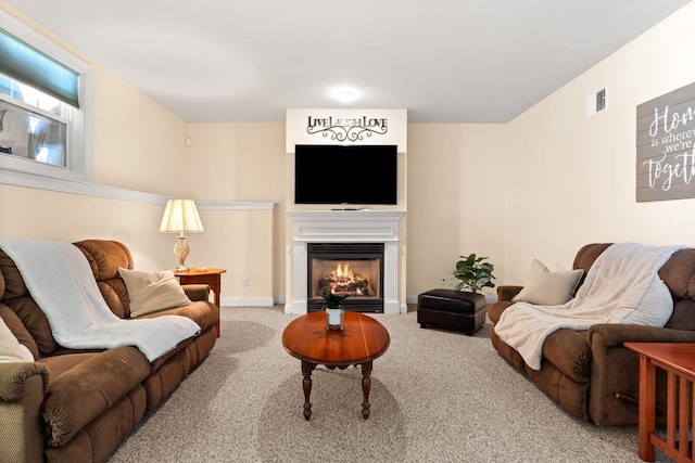 carpeted living room featuring visible vents, baseboards, and a lit fireplace